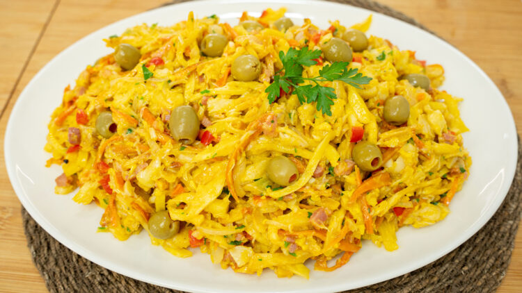 Travessa de servir recheada com Bacalhau à Assis muito cremoso e húmido, onde sobressaem os tons laranjas da cenoura e amarelos dos ovos, decorado no topo com um raminho de salsa fresca e azeitonas verdes recheadas com pimento.