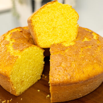 Um bolo de buraco clássico, com uma crosta dourada e perfeitamente cozida, desenformado sobre um prato branco de pé alto, pronto a ser servido.