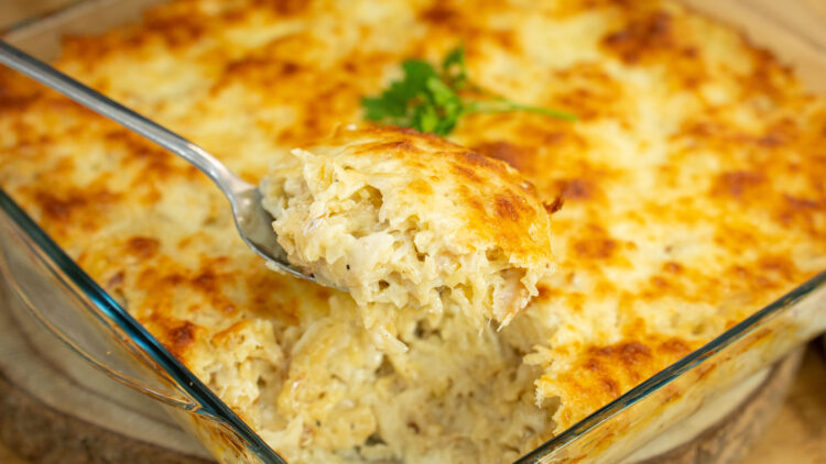 Travessa retangular de vidro cheia de bacalhau com natas, acabada de sair do forno, com uma crosta generosa de queijo mozarela derretido e gratinado num tom dourado irresistível.